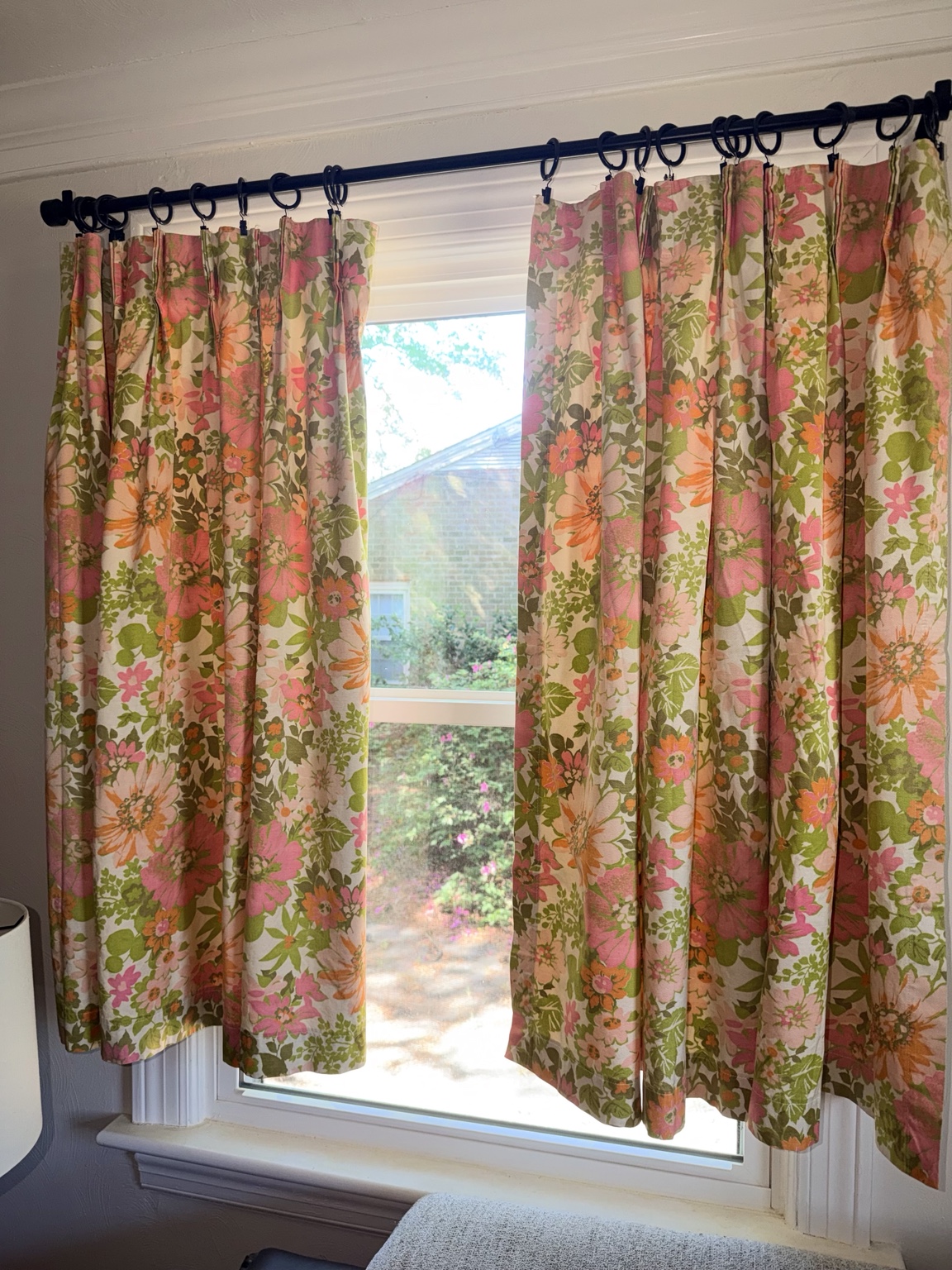 Vintage pink, orange and green floral curtain panels hanging in a window